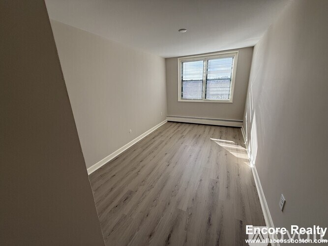 A room with wooden flooring and a window.