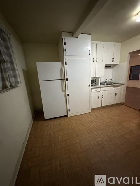 A kitchen area with a white fridge and cabinets.