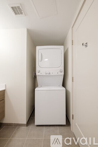 A white toilet with a bidet attachment is in a small bathroom.