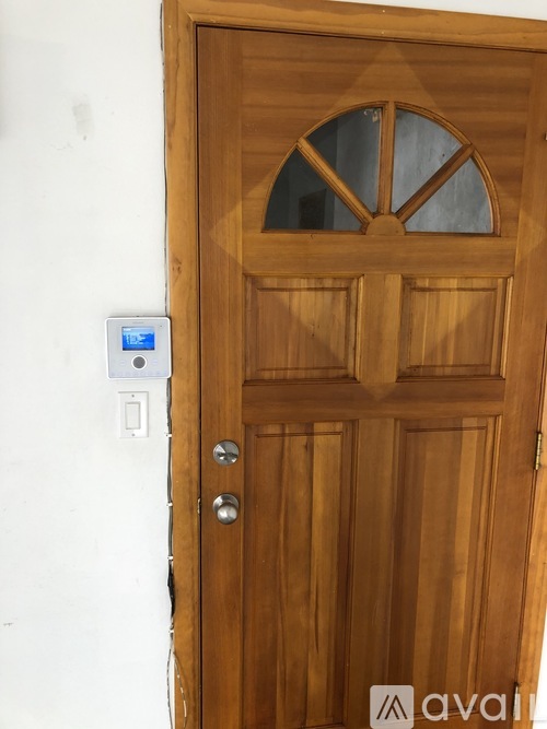 A wooden door with a glass window and a digital lock.