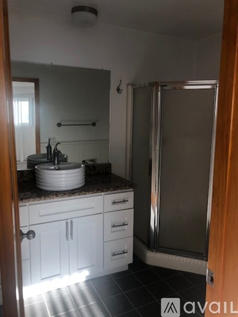 A bathroom with a sink, mirror, and shower.