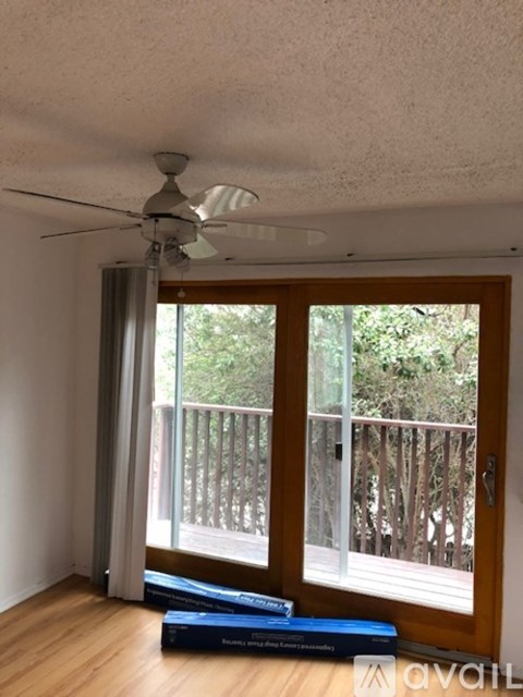 A room with a ceiling fan and a window with a view of a deck.