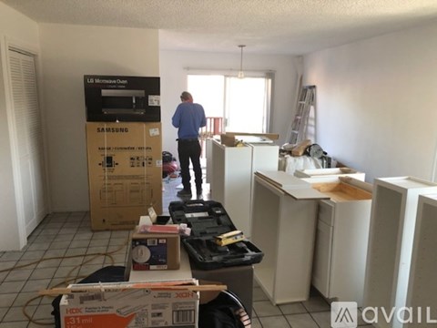 A man is standing in a room with boxes and appliances on the floor.