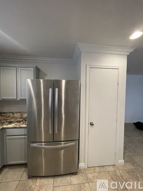 A stainless steel refrigerator in a kitchen with white cabinets.