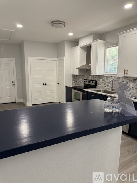 A kitchen with white cabinets and a dark countertop.