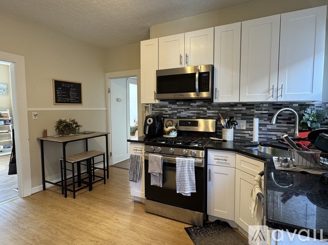 A kitchen with white cabinets and black countertops.