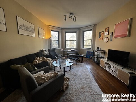 A living room with a couch, chairs, and a television.