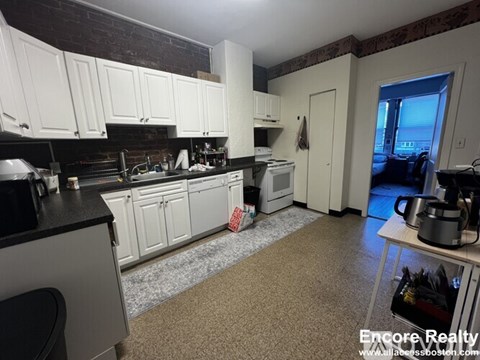 A kitchen with white cabinets and a black counter top.