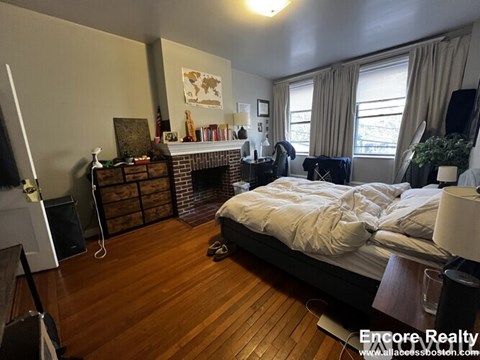 A bedroom with a large bed and a fireplace.