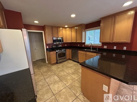 A kitchen with brown cabinets and black countertops.