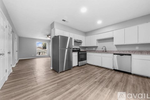 A modern kitchen with white cabinets and a wooden floor.
