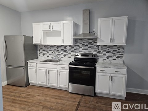 A kitchen with white cabinets and a black and white tiled backsplash.