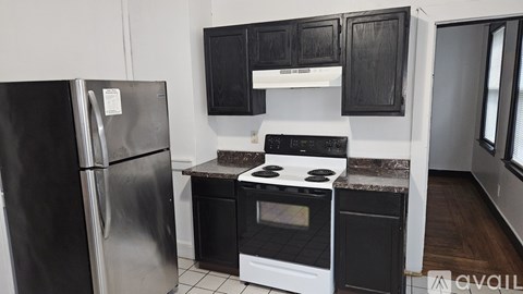 A black fridge stands next to a black oven in a kitchen.