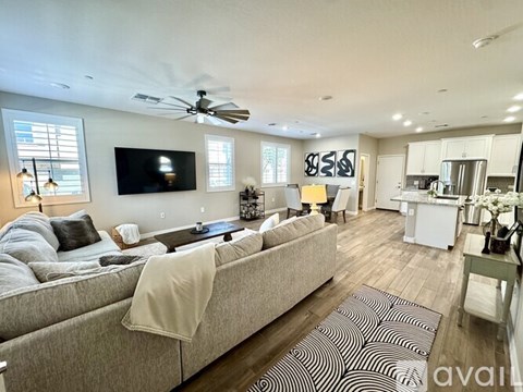 A living room with a grey couch and a television on the wall.