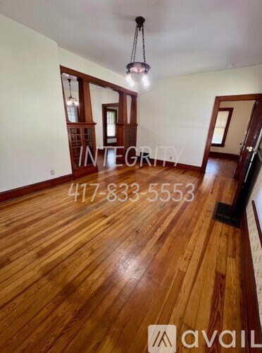 A room with wooden floors and a large window with a view of the sky.