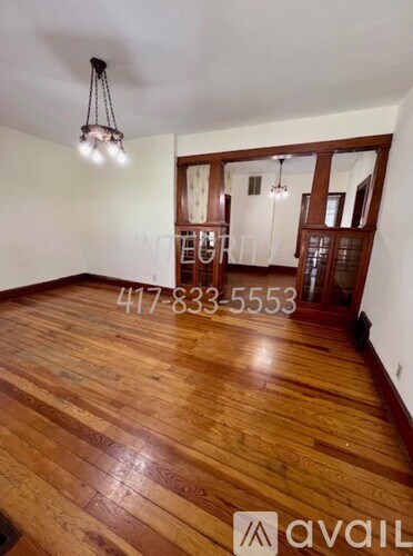 A room with wooden flooring and a chandelier hanging from the ceiling.