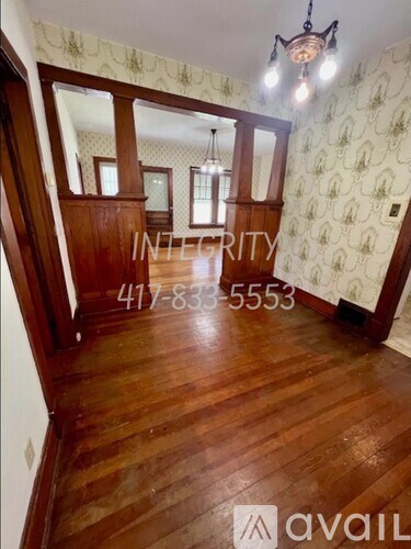 A room with wooden floors and a chandelier with INTEGRITY written on the wall.
