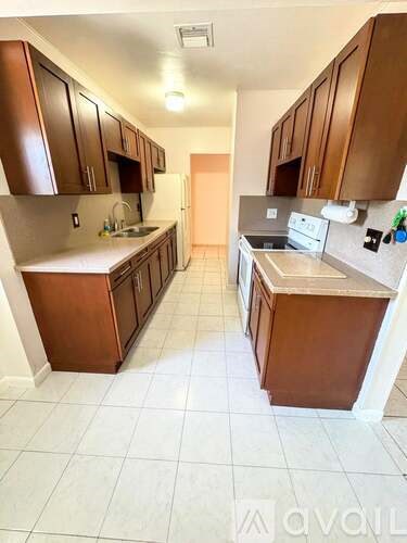 A kitchen with brown cabinets and white tile flooring.