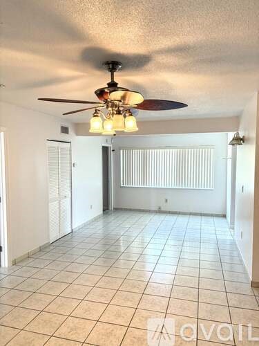 A room with a ceiling fan and tiled flooring.