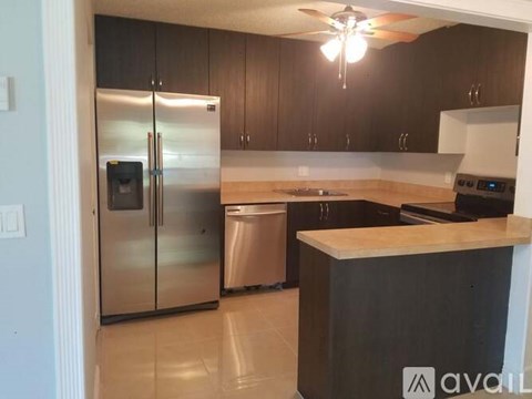 A kitchen with a stainless steel refrigerator and a black countertop.