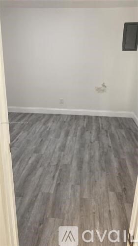 A room with a wooden floor and a wall-mounted TV.