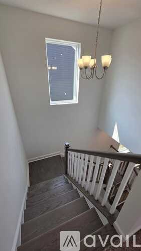 A staircase with a chandelier and a window.