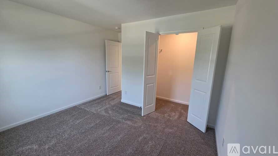 A room with a carpeted floor and two doors, one of which is open.