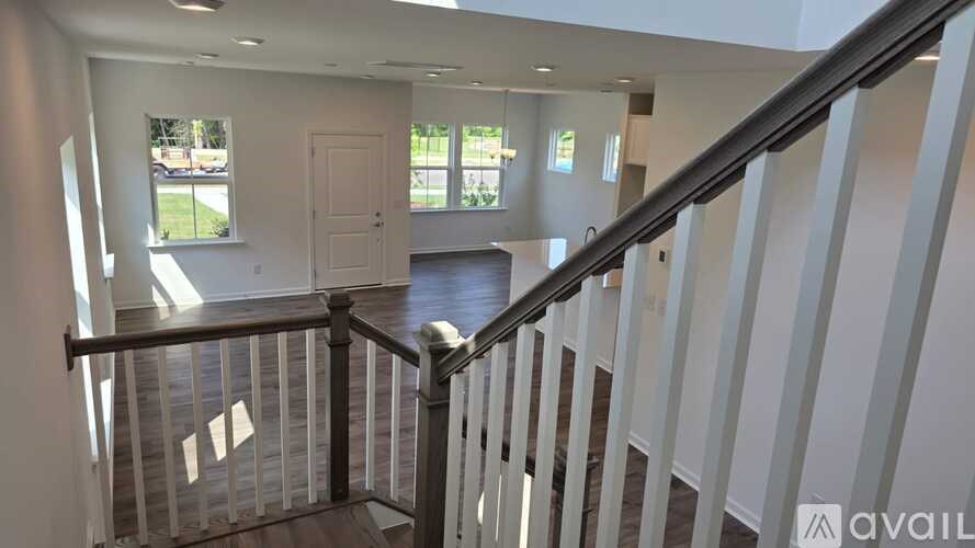 A staircase with a railing leads to a bright room with a large window.