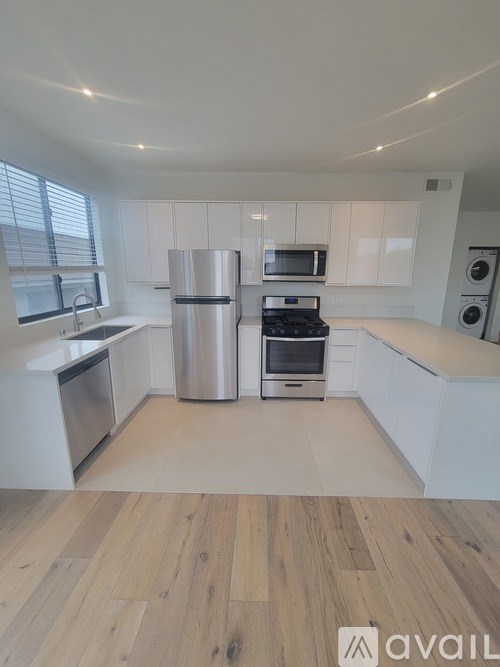 A kitchen with white cabinets and a wooden floor.
