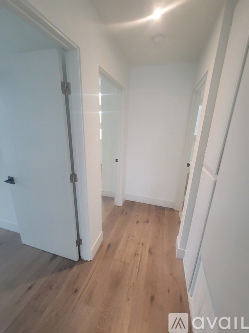 A hallway with a white door and wooden floors.