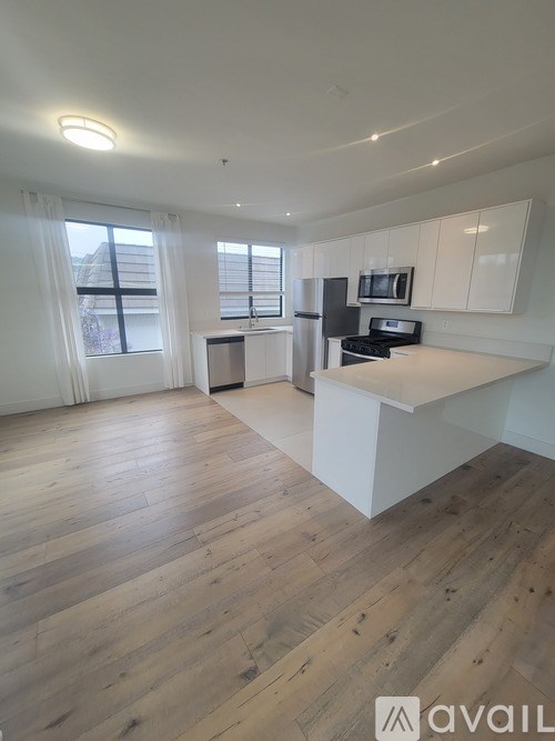 A spacious kitchen with wooden floors and white cabinets.