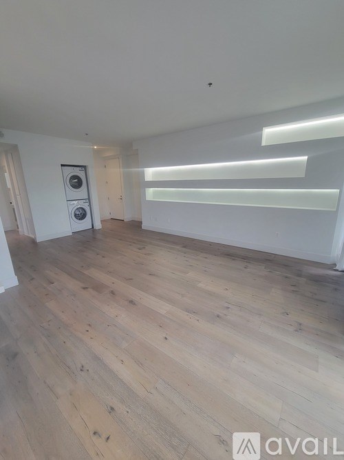 A room with wooden flooring and a washing machine on the wall.