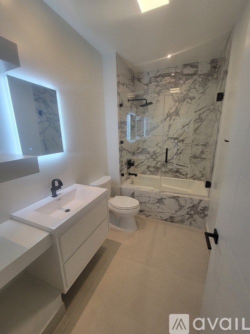 A bathroom with marble tiles on the walls and a white sink.