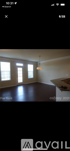 A room with a large window and a hanging light fixture is available for rent.