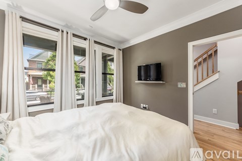 A bedroom with a bed, a ceiling fan, and a window with curtains.