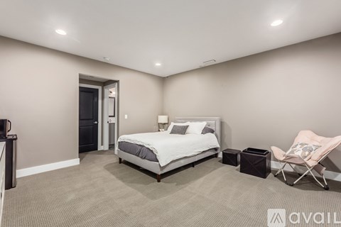 A bedroom with a bed, chair, and nightstand.
