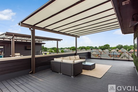 A patio with a white couch and a table under a white awning.