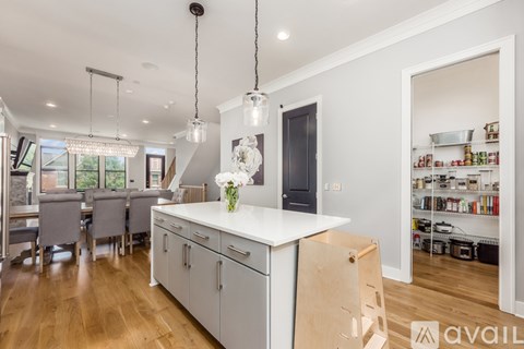 A modern kitchen with wooden floors and white cabinetry.