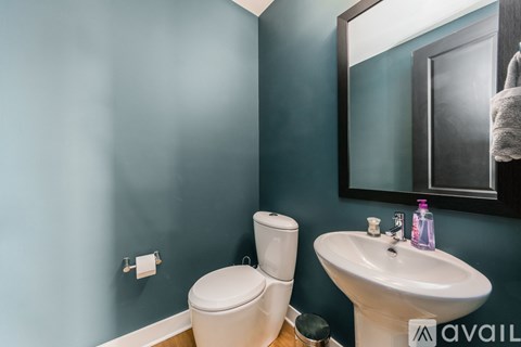 A bathroom with a toilet, sink, and mirror.