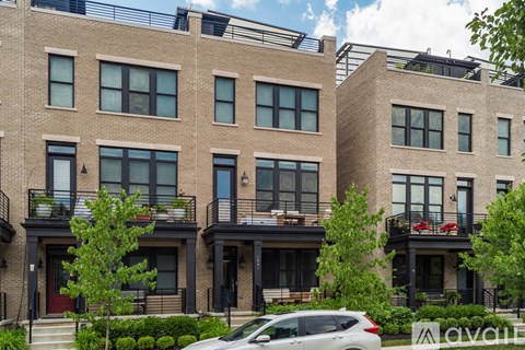 A row of apartment buildings with balconies and a car parked in front.
