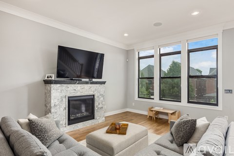 A living room with a grey couch, a white fireplace, and a television.