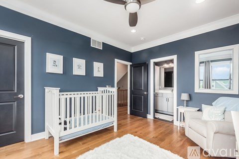 A baby's room with a white crib and a white chair.