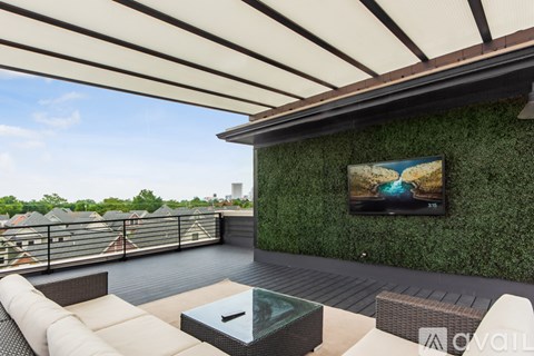 A patio with a couch, table, and television on a green wall.