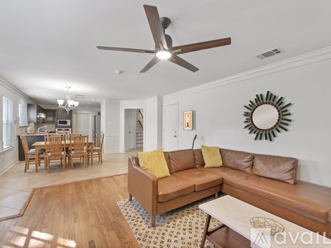 A living room with a brown couch and a ceiling fan.