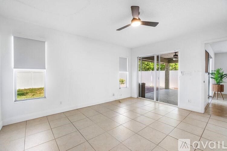 A spacious room with a ceiling fan and sliding glass doors leading to a balcony.
