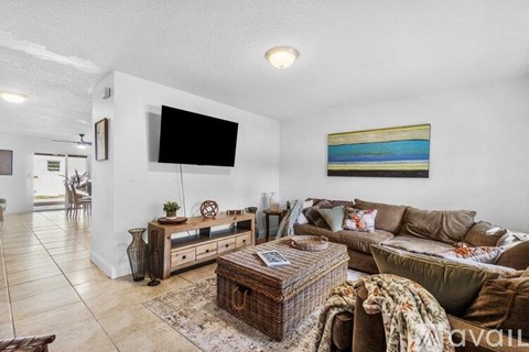 A living room with a brown couch and a flat screen TV mounted on the wall.