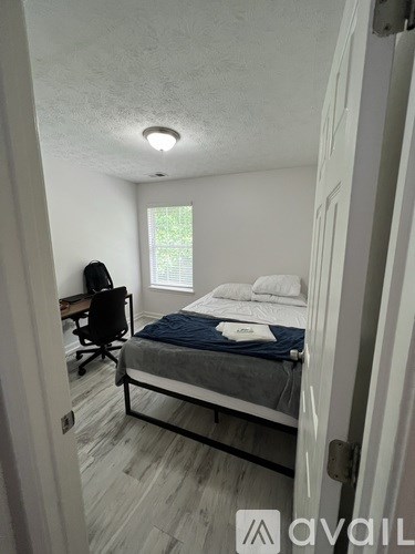 A bedroom with a bed, desk, and window.