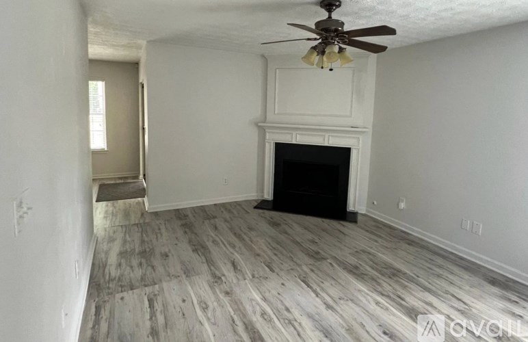 A living room with a fireplace and a ceiling fan.