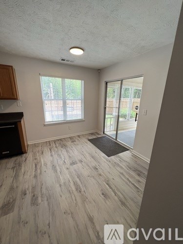 A room with a wooden floor and a sliding glass door leading outside.