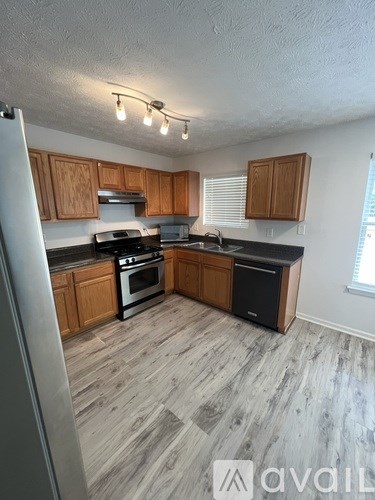 A kitchen with wooden cabinets and a grey floor.
